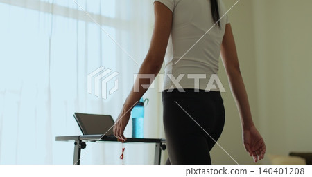 Woman having workout on treadmill back view. Fitness, girl and walking on treadmill in home for cardio exercise, wellness challenge and burning calories. Woman having workout on treadmill back view. Fitness, girl and walking on treadmill in home for cardio exercise, wellness challenge and burning calories. 140401208