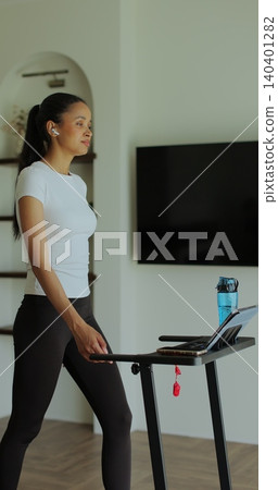Vertical video. Workout, woman and walking on treadmill in home for cardio exercise, fitness challenge and burning calories. Vertical video. Workout, woman and walking on treadmill in home for cardio exercise, fitness challenge and burning calories. 140401282