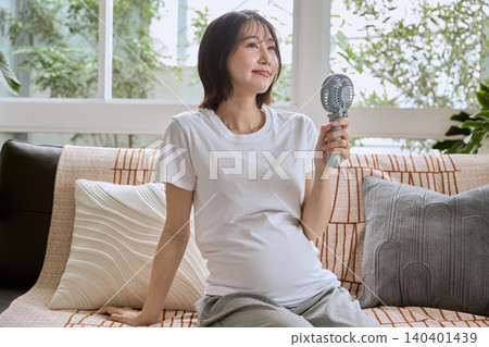 一位孕婦用手持風扇為自己降溫。 一位孕婦用手持風扇為自己降溫。 140401439