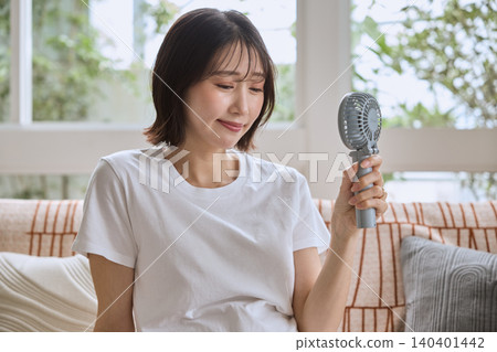 A pregnant woman cools herself with a portable fan in the hot summer. A pregnant woman cools herself with a portable fan in the hot summer. 140401442