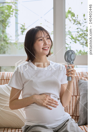 一位孕婦用便攜式風扇為自己降溫。 一位孕婦用便攜式風扇為自己降溫。 140401446