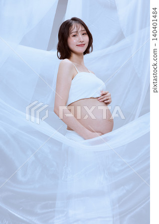 A pregnant woman wrapped in white cloth; a peaceful image of maternity. A pregnant woman wrapped in white cloth; a peaceful image of maternity. 140401484