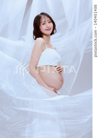 A pregnant woman wrapped in white cloth; a peaceful image of maternity. A pregnant woman wrapped in white cloth; a peaceful image of maternity. 140401486