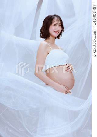 A pregnant woman wrapped in white cloth; a peaceful image of maternity. A pregnant woman wrapped in white cloth; a peaceful image of maternity. 140401487