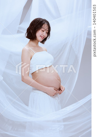 A pregnant woman wrapped in white cloth; a peaceful image of maternity. A pregnant woman wrapped in white cloth; a peaceful image of maternity. 140401503
