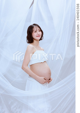 一位孕婦裹著白布,展現了寧靜祥和的孕育景象。 一位孕婦裹著白布,展現了寧靜祥和的孕育景象。 140401508