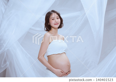 A pregnant woman wrapped in white cloth; a peaceful image of maternity. A pregnant woman wrapped in white cloth; a peaceful image of maternity. 140401523