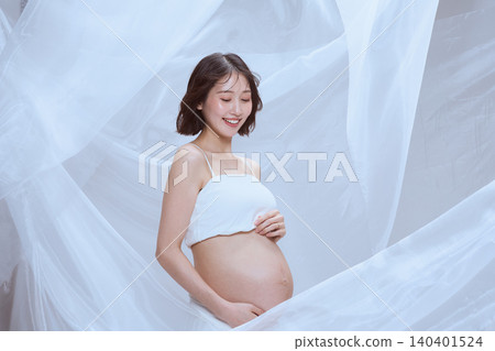 一位孕婦裹著白布,展現了寧靜祥和的孕育景象。 一位孕婦裹著白布,展現了寧靜祥和的孕育景象。 140401524