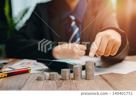 Professional Businessman Analyzing Financial Growth with Stacked Coins and Calculator on Desk, Business concept Professional Businessman Analyzing Financial Growth with Stacked Coins and Calculator on Desk, Business concept 140401751