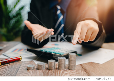 Business Professional Analyzing Financial Growth with Coins and Calculator in Modern Office Setting, Business concept Business Professional Analyzing Financial Growth with Coins and Calculator in Modern Office Setting, Business concept 140401752