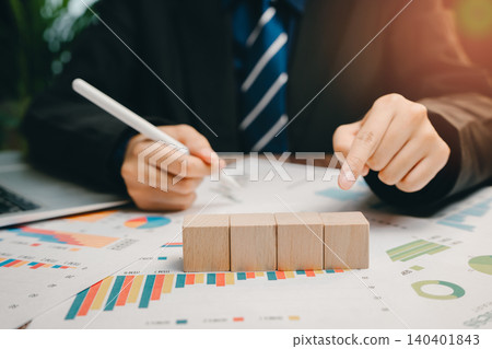 Businessman Analyzing Financial Data with Wooden Blocks on Table Surrounded by Charts and Graphs, Business concept Businessman Analyzing Financial Data with Wooden Blocks on Table Surrounded by Charts and Graphs, Business concept 140401843