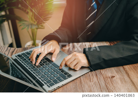 Business Person Working on Laptop at Modern Office Desk with Green Plant in Background, Business concept Business Person Working on Laptop at Modern Office Desk with Green Plant in Background, Business concept 140401863