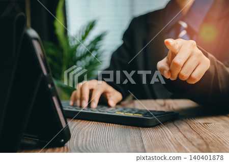 Professional Businessman Pointing at the Camera While Working on a Laptop in Modern Office Setting, Business concept Professional Businessman Pointing at the Camera While Working on a Laptop in Modern Office Setting, Business concept 140401878