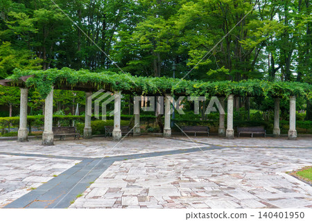 A wisteria trellis made of Oya stone at the entrance to a lush green park. A wisteria trellis made of Oya stone at the entrance to a lush green park. 140401950