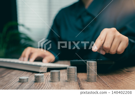 Person Using Calculator for Financial Planning with Stacks of Coins on Wooden Desk, Business concept Person Using Calculator for Financial Planning with Stacks of Coins on Wooden Desk, Business concept 140402208