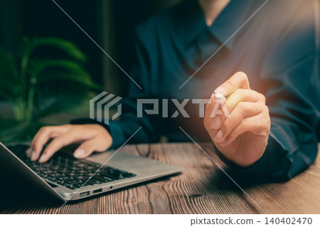 Close-Up of Hand Holding Pen Near Laptop on Wooden Table in Modern Office Setting, Business concept Close-Up of Hand Holding Pen Near Laptop on Wooden Table in Modern Office Setting, Business concept 140402470