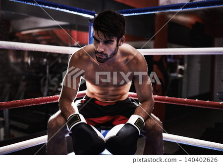 MMA, boxer and man sitting in ring ready for challenge, competitive and confident from training in gym. Male person, healthy and fitness from practice in exercise studio as athlete and fighter MMA, boxer and man sitting in ring ready for challenge, competitive and confident from training in gym. Male person, healthy and fitness from practice in exercise studio as athlete and fighter 140402626