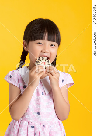 Cute Asian little girl eating sweet cookie, studio yellow background, happy smiling child enjoying dessert, childhood lifestyle concept Cute Asian little girl eating sweet cookie, studio yellow background, happy smiling child enjoying dessert, childhood lifestyle concept 140403592