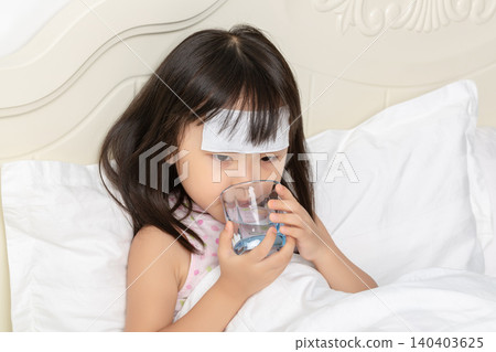 Sick Asian Little Girl Drinking Water in Bed with Fever Patch 140403625