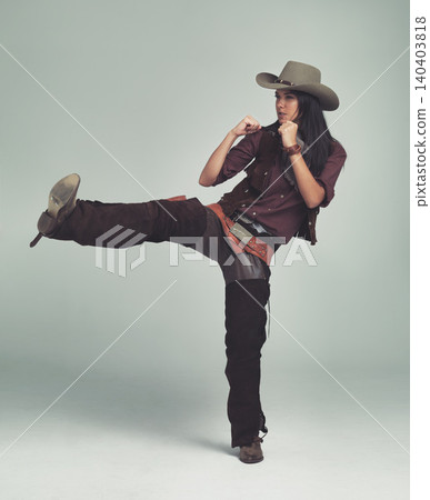 Cowgirl, kick and fight with fists in studio for western character, wild west outfit and hat for sheriff. Female person, costume and angry with aggression, rage and isolated with grey background Cowgirl, kick and fight with fists in studio for western character, wild west outfit and hat for sheriff. Female person, costume and angry with aggression, rage and isolated with grey background 140403818