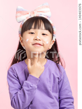 A studio photo of an Asian girl applying face cream after washing her face. A studio photo of an Asian girl applying face cream after washing her face. 140403976