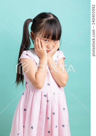 Angry and frustrated young girl staring forward while holding her face in her hands. Angry and frustrated young girl staring forward while holding her face in her hands. 140403992