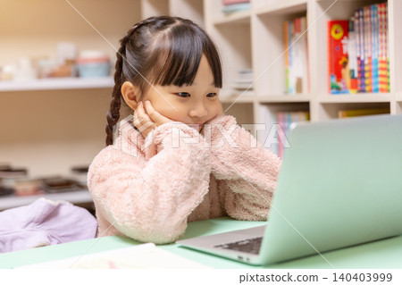 Focused girl looking attentively at a laptop screen during an online school class at home. Focused girl looking attentively at a laptop screen during an online school class at home. 140403999