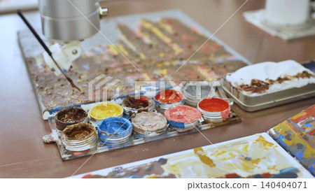 Artist's creative workspace with colorful paint jars and palettes Artist's creative workspace with colorful paint jars and palettes 140404071