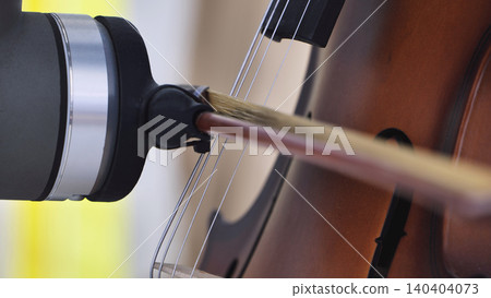 Microphone recording a classical cello. Close up of bow on strings and instrument 140404073
