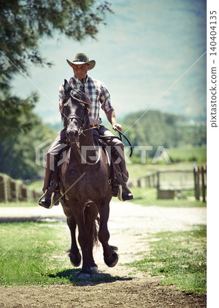 Cowboy, summer and man riding horse with saddle on field in countryside for equestrian training. Nature, western and rodeo with mature horseback rider on animal at ranch outdoor in rural Texas 140404135