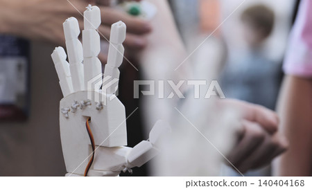A person controls an artificial robotic arm via wires on their hand. 140404168