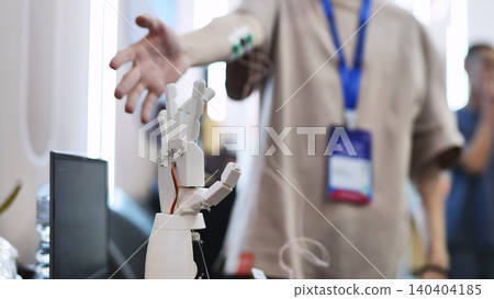 A person controls an artificial robotic arm via wires on their hand. 140404185