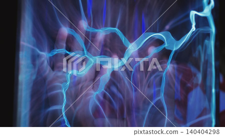 Hand touching a plasma ball generating blue light electricity and energy sparks 140404298