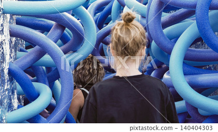 People observing a captivating modern art installation with blue interconnected tubes People observing a captivating modern art installation with blue interconnected tubes 140404303