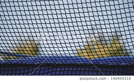 Trampoline safety net creating a protective grid pattern in backyard for children 140404318