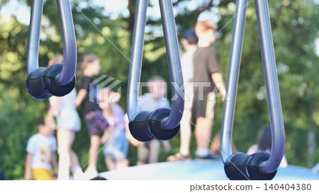 Playground rings with blurred children playing outdoors in summer Playground rings with blurred children playing outdoors in summer 140404380