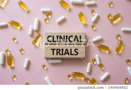 CLINICAL TRIALS symbol. Concept word CLINICAL TRIALS on wooden blocks. Beautiful pink background with pills. Medicine and CLINICAL TRIALS. Copy space CLINICAL TRIALS symbol. Concept word CLINICAL TRIALS on wooden blocks. Beautiful pink background with pills. Medicine and CLINICAL TRIALS. Copy space 140404402