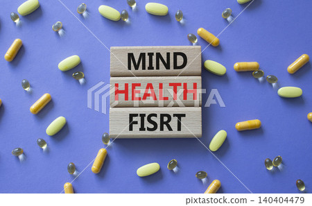 Mind Health First symbol. Concept words Mind Health First on wooden blocks. Beautiful purple background with pills. Healthcare and Mind Health First concept. Copy space. Mind Health First symbol. Concept words Mind Health First on wooden blocks. Beautiful purple background with pills. Healthcare and Mind Health First concept. Copy space. 140404479