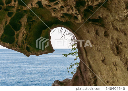 The blue sea viewed through a hole in a strangely shaped rock carved by wave erosion. The blue sea viewed through a hole in a strangely shaped rock carved by wave erosion. 140404640