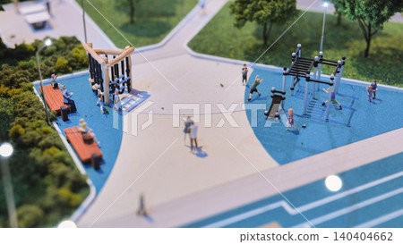 Urban planning model showing a modern playground with miniature people and benches 140404662