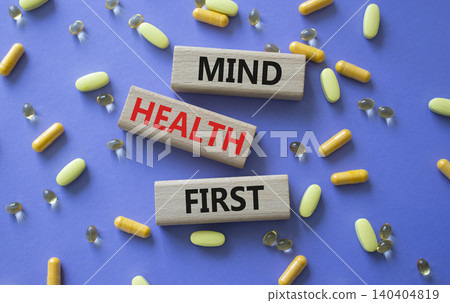 Mind Health First symbol. Concept words Mind Health First on wooden blocks. Beautiful purple background with pills. Healthcare and Mind Health First concept. Copy space. Mind Health First symbol. Concept words Mind Health First on wooden blocks. Beautiful purple background with pills. Healthcare and Mind Health First concept. Copy space. 140404819
