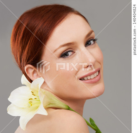 Portrait, skincare and happy woman with flower, lily and natural beauty isolated on a gray studio background. Face, organic and ginger model with floral cosmetics for dermatology, wellness and makeup 140404824