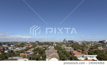 A sunny autumn day over a typical Australian residential neighborhood in Melbourne. Panoramic view of suburban homes, green trees, and the distant metropolitan horizon under a clear sky. A sunny autumn day over a typical Australian residential neighborhood in Melbourne. Panoramic view of suburban homes, green trees, and the distant metropolitan horizon under a clear sky. 140404868
