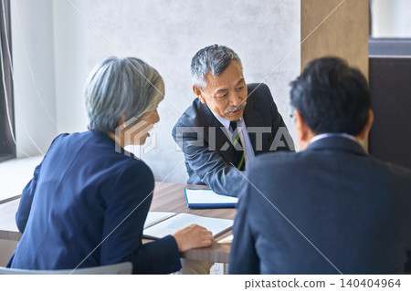 高階業務團隊在會議室討論文件。 高階業務團隊在會議室討論文件。 140404964