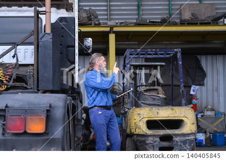 Truck mechanic performing maintenance inspection with digital checklist at industrial workshop Truck mechanic performing maintenance inspection with digital checklist at industrial workshop 140405845