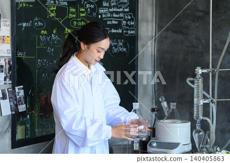 Young Asian Woman Scientist in White Lab Coat Working with Distillation Equipment at Craft Gin Workshop Laboratory Young Asian Woman Scientist in White Lab Coat Working with Distillation Equipment at Craft Gin Workshop Laboratory 140405863