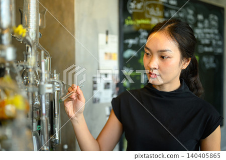 Young Asian Female Scientist Examining Glass Laboratory Equipment in Modern Research Facility Young Asian Female Scientist Examining Glass Laboratory Equipment in Modern Research Facility 140405865