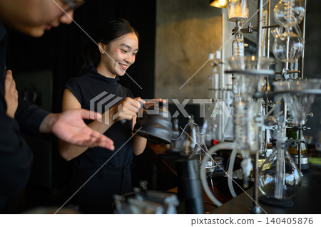 Smiling Asian Female Barista Using Gooseneck Kettle at Specialty Coffee Bar with Siphon Brewing Equipment Smiling Asian Female Barista Using Gooseneck Kettle at Specialty Coffee Bar with Siphon Brewing Equipment 140405876