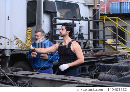 Industrial technicians checking truck coupling systems and maintenance workflow at transport workshop Industrial technicians checking truck coupling systems and maintenance workflow at transport workshop 140405882