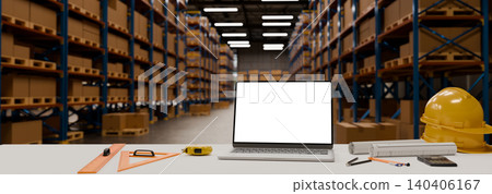 Engineering workspace empty screen laptop computer with safety equipment and drafting tools inside modern warehouse Engineering workspace empty screen laptop computer with safety equipment and drafting tools inside modern warehouse 140406167